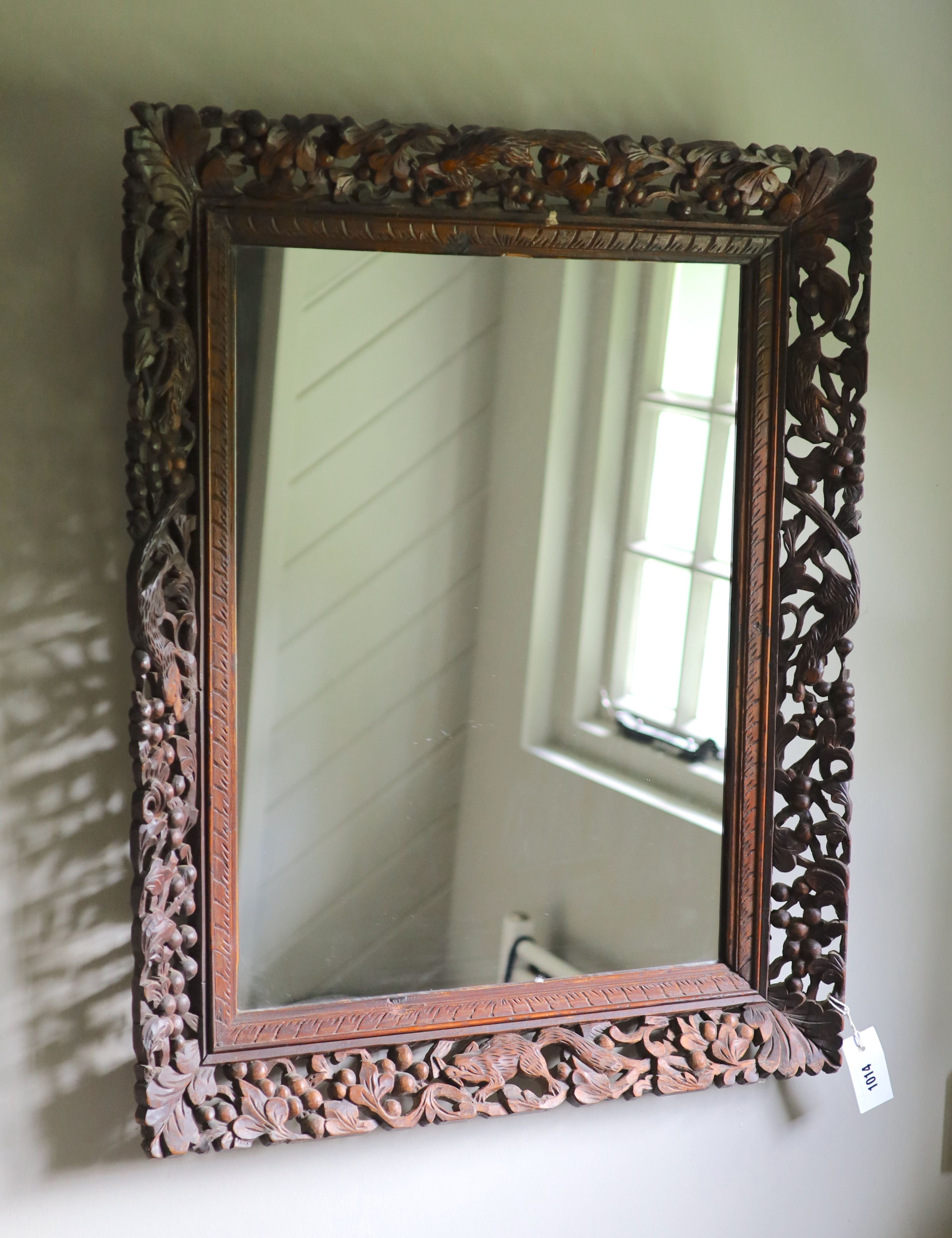 A Continental hardwood wall mirror, carved and pierced with squirrels and fruit, width 77cm height 63cm